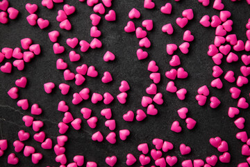 Pink heart sugar sprinkles scattered on dark