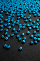 Blue star sugar sprinkles scattered on dark