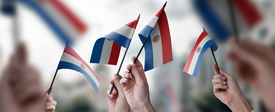 A group of people holding small flags of the Paraguay in their hands