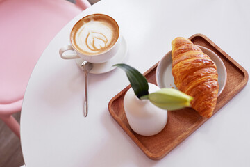 Сup of coffee and a croissant in a cafe.