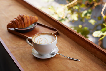 Сup of coffee and a croissant in a cafe.