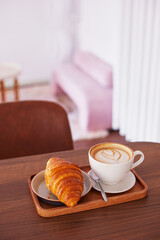 Сup of coffee and a croissant in a cafe.