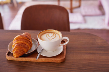 Сup of coffee and a croissant in a cafe.