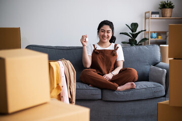 Satisfied homeowner. portrait of happy young asian woman buyer renter of new modern home apartment holding key demonstrating wellbeing wealth celebrate achievement