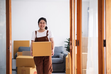 New house, moving and asian woman carrying boxes while feeling proud and excited about buying a house with a mortgage loan. Young asian woman first time buyers unpacking in dream home, apartment