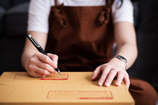 New house, asian woman wrighting on the boxes while feeling proud and excited about buying a house with a mortgage loan. Young asian woman first time buyers unpacking in dream home, apartment
