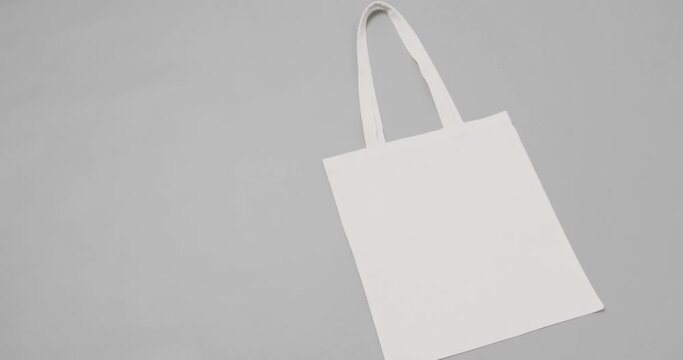 Close up of white bag on grey background, with copy space, slow motion