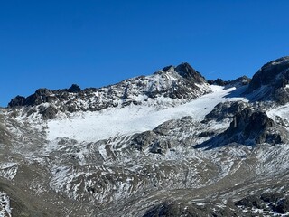 First snow on the rocky mountain peak Piz Sarsura (3175 m) in the Albula Alps and above the alpine valley Val Grialetsch, Zernez - Canton of Grisons, Switzerland (Kanton Graubünden, Schweiz)