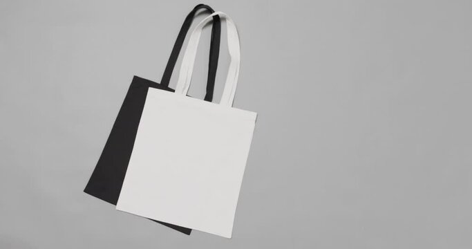 Close up of white and black bags on grey background, with copy space, slow motion