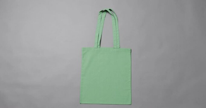 Close up of green bag on grey background, with copy space, slow motion