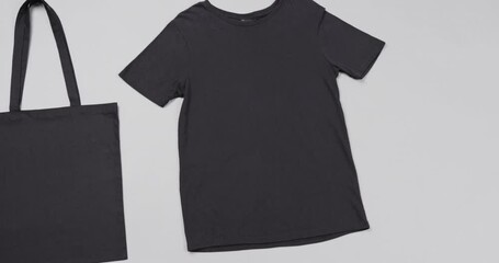 Close up of black bag and t-shirt on white background, with copy space, slow motion