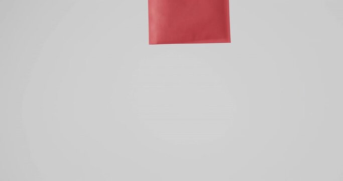 Hand of caucasian woman holding red bag on white background, copy space, slow motion