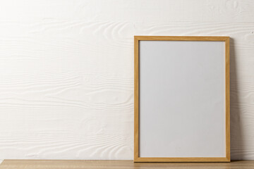 Wood empty frame with copy space on table against white wall