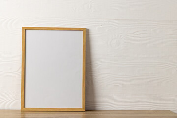 Wood empty frame with copy space on table against white wall