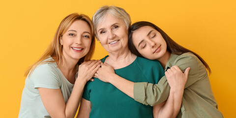 Portrait of happy mature woman with her daughter and mother on yellow background