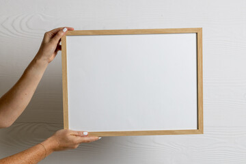 Hands holding wood empty frame with copy space against white wall