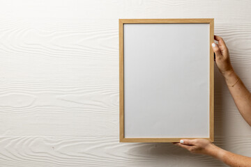 Hands holding wood empty frame with copy space against white wall