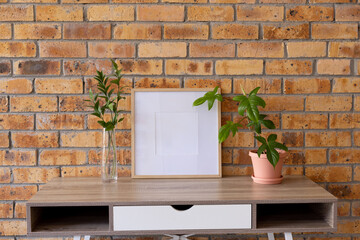 Wood empty frame with copy space and plants in pots on desk against brick wall