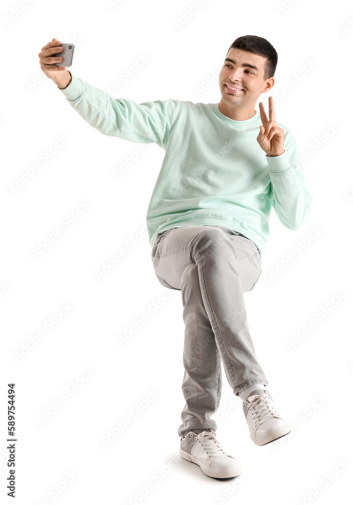 Poster Handsome guy with mobile phone taking selfie in chair on white background