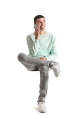 Handsome guy talking by mobile phone in chair on white background