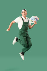 Male painter with color palettes jumping on green background