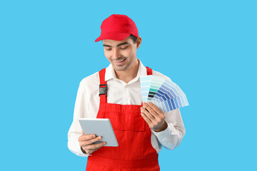 Male painter with color palettes and tablet computer on blue background