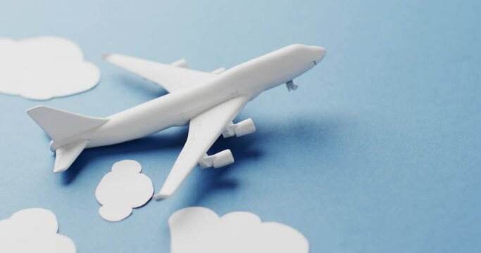 Close up of white airplane model with white clouds and copy space on blue background