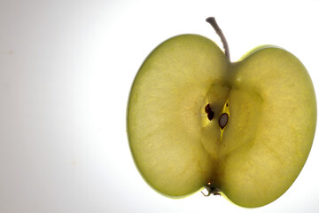 Green apple with seed half slice cross section macro closeup backlight on white background