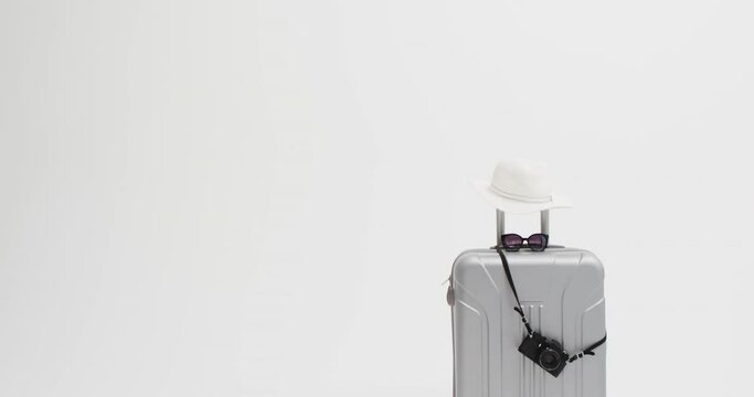Close up of suitcase, camera, sunglasses and sunhat with copy space on white background