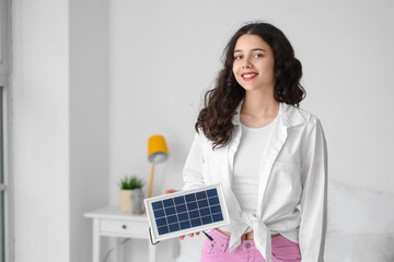 Teenage girl with portable solar panel in bedroom