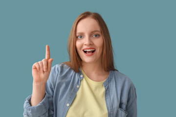 Beautiful redhead woman pointing at something on blue background