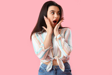 Surprised young woman in shirt on pink background