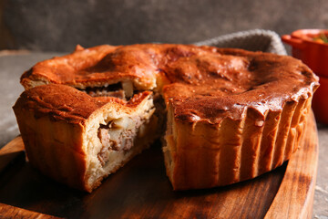 Board with delicious meat pie on grey grunge table