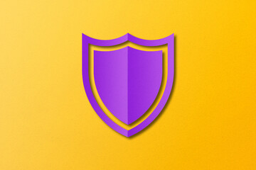 purple paper shield Punched paper cut out shield shape set on yellow paper background.