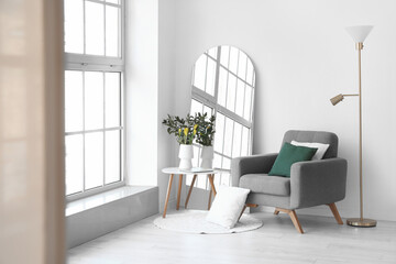 Interior of living room with mirror, armchair and tulips in vase