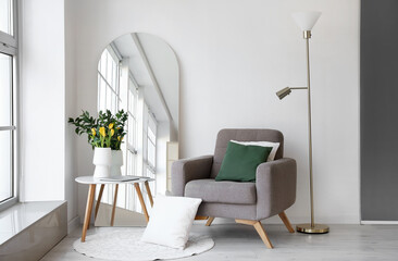 Interior of living room with mirror, armchair and tulips in vase