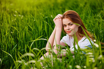 adorable woman sitting in nature resting in tall grass