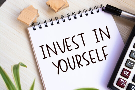 Economy and business concept. On the table are reports, pencils and a notebook with the inscription - INVEST IN YOURSELF