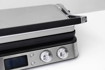 Modern electric grill with closed lid on white table, closeup