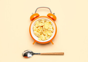 Creative composition with alarm clock, corn flakes and spoon on color background