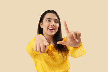 Fototapeta na wymiar Young woman showing loser gesture on beige background