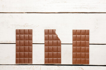 Bars of tasty chocolate on light wooden background