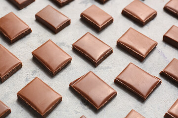 Composition with pieces of tasty chocolate on light background, closeup