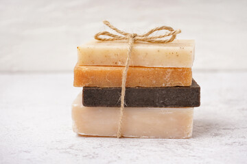 Stack of natural soap bars tied with rope on light background