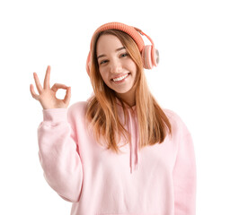 Young woman in headphones showing OK on white background