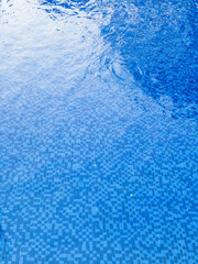 Patterned blue tiles on floor of pool under water, water making a natural rippling effect