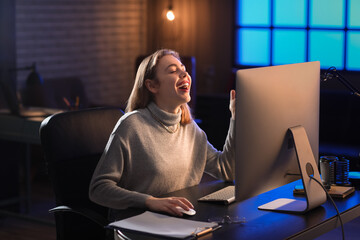 Happy female programmer working with computer in office at night