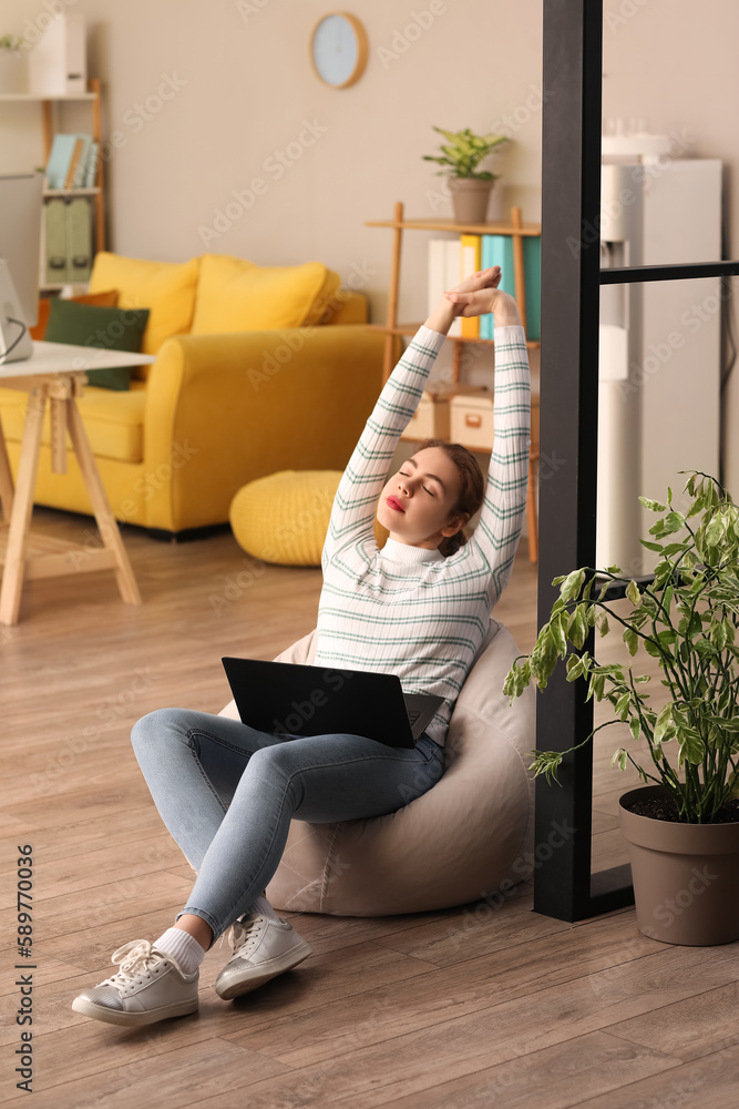 Poster female programmer with laptop stretching in office