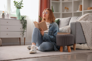 Young woman reading book on floor at home