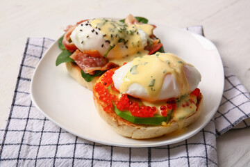 Plate with tasty eggs Benedict on white wooden table, closeup